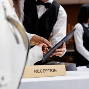 A photo of a hotel reception desk; guest signing an iPad.