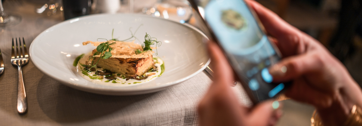 Photo of guest taking a photo of her fine dining dish at a restaurant