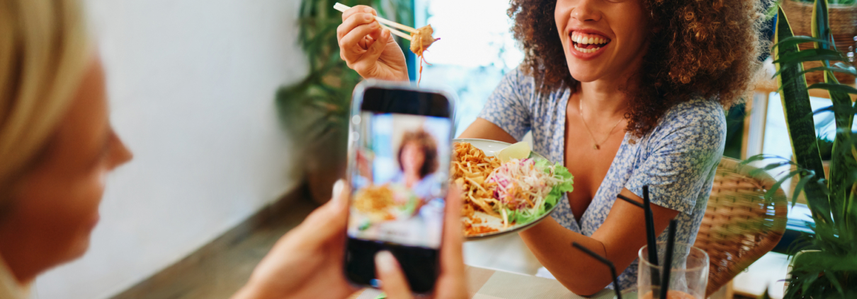 Two friends capturing a fun dining moment with a smartphone